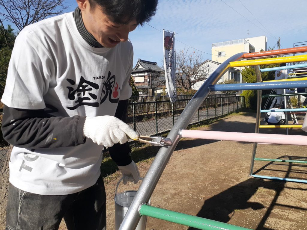 写真：小学校の雲梯を塗装する満天スタッフ