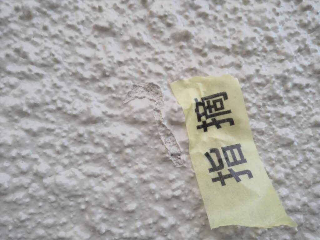 写真：外壁の施工不良個所に指摘テープを貼る