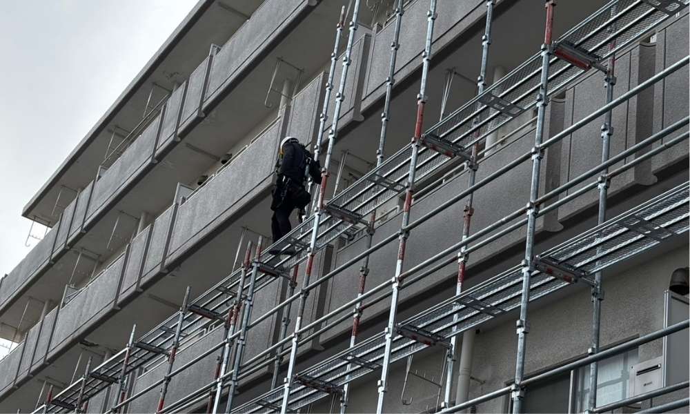新潟市中央区のマンションの外壁塗装工事の足場組立作業中の様子。