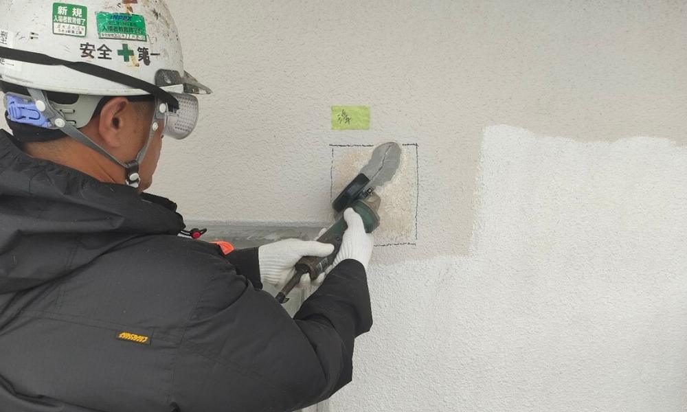外壁ひび割れにサンダーでUカット作業をする職人