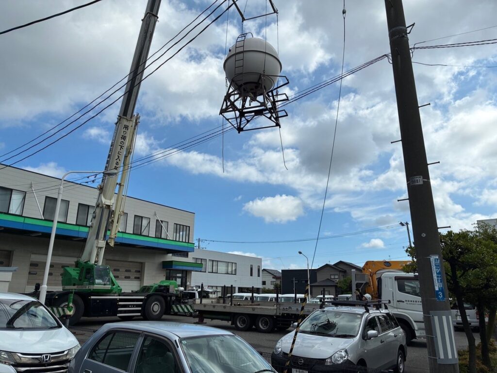 マンション大規模修繕で屋上タンクをクレーンで吊り上げている様子